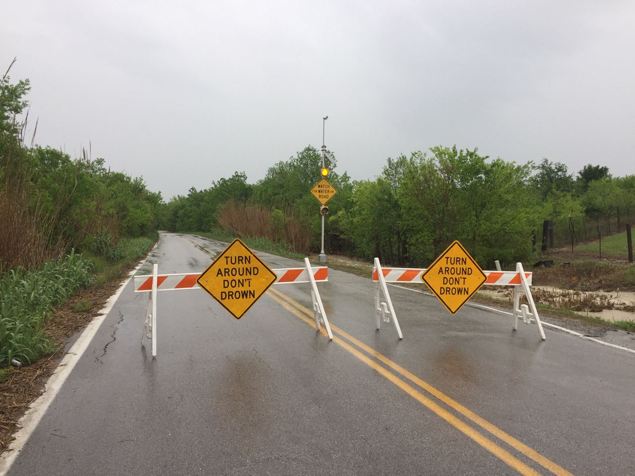 A sign tells drivers to "Turn Around Don't Drown" while the low water crossing is closed. 