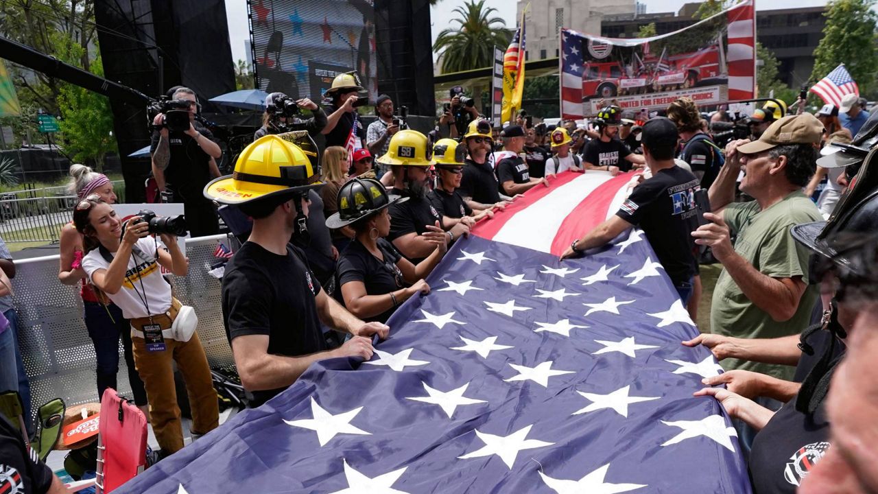 Firefighters with Bravest for Choice prepare to fold a large U.S. flag as they protest vaccination mandates designed to slow the spread of COVID-19 in Los Angeles on Sunday. (AP Photo/Damian Dovarganes)