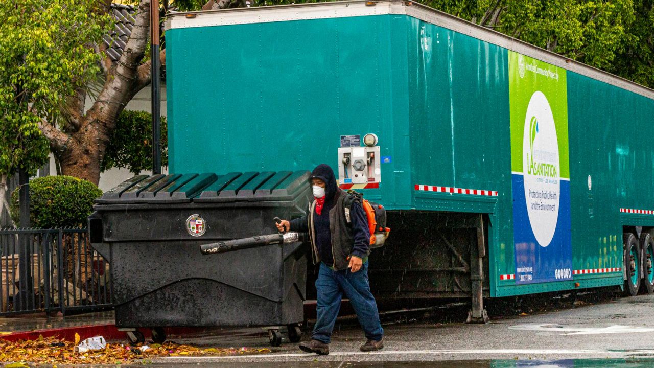 A worker uses a blower to clear debris at Placita Olvera Church next to a mobile sanitation station in downtown Los Angeles on April 10, 2020, during the coronavirus outbreak. (AP Photo/Damian Dovarganes)