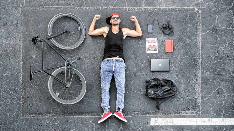 FILE- Man in his 20s laying on ground with bike and various electronic devices. 