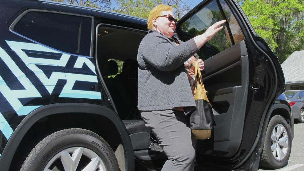 In this photo taken March 7, 2018 shows Cinzhasha Farmer, who is blind, exiting a vehicle equipped with software meant to help the visually impaired interact with self-driving cars in Ocala, Fla. The 41-year-old was eager to participate in the study so she can one day drive without relying on others."It's one of my goals and I don't know how I'll ever accomplish it, but that car may do it," she said with a smile. (AP Photo/Jason Dearen)