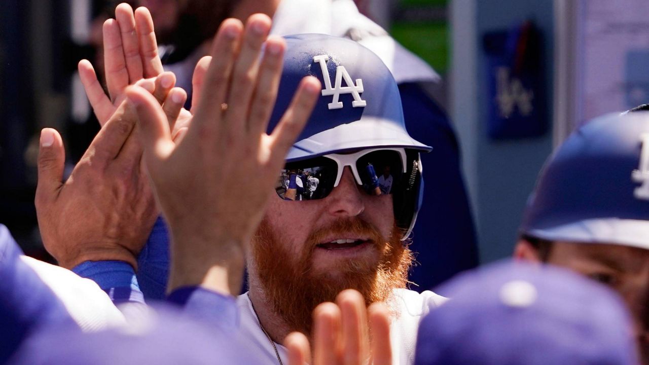 Los Angeles Dodgers' Justin Turner is congratulated by teammates in the dugout after scoring on a double by Chris Taylor during the fourth inning of their game against the Cincinnati Reds Sunday in LA. (AP Photo/Mark J. Terrill)