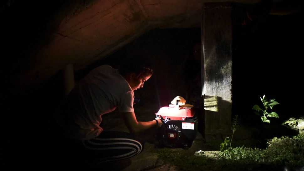 FILE - In this Dec. 21, 2017 filw photo, barrio Patron resident Karina Santiago Gonzalez works on a small power plant in Morovis, Puerto Rico.  (AP Photo/Carlos Giusti, File)