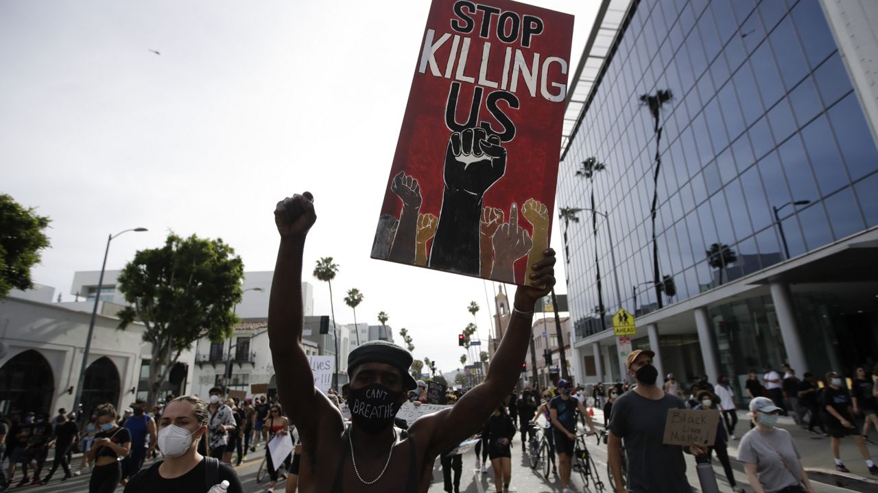A protester carries a sign in the Hollywood area of Los Angeles during demonstrations over the death of George Floyd, who died May 25 after being restrained by Minneapolis police. (AP Photo/Marcio Jose Sanchez)