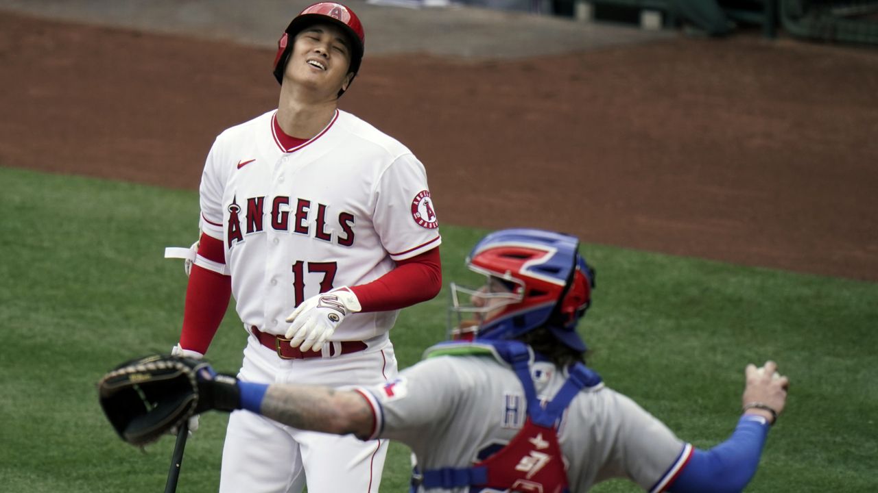 Los Angeles Angels' Shohei Ohtani, top, of Japan, reacts after striking out as Texas Rangers catcher Jonah Heim throws the ball to starting pitcher Mike Foltynewicz during the first inning of a baseball game, Wednesday, April 21, 2021, in Anaheim, Calif. (AP Photo/Jae C. Hong)
