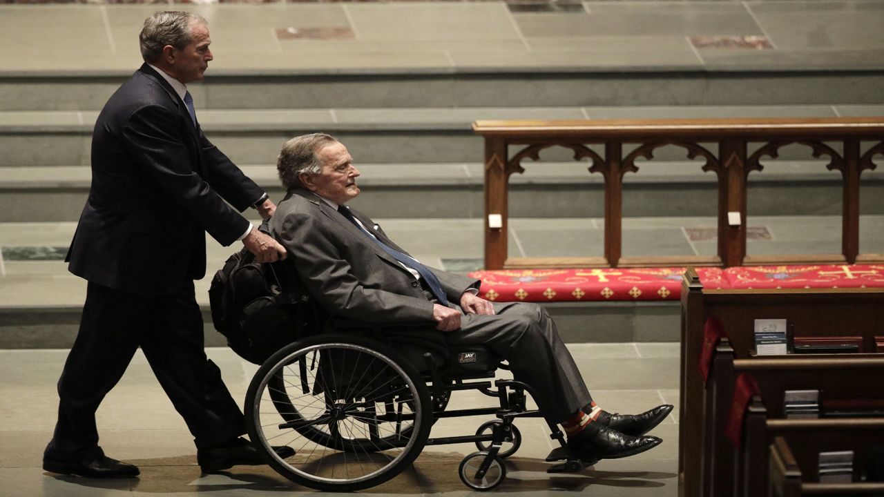 George H.W. Bush, right, in a wheelchair.