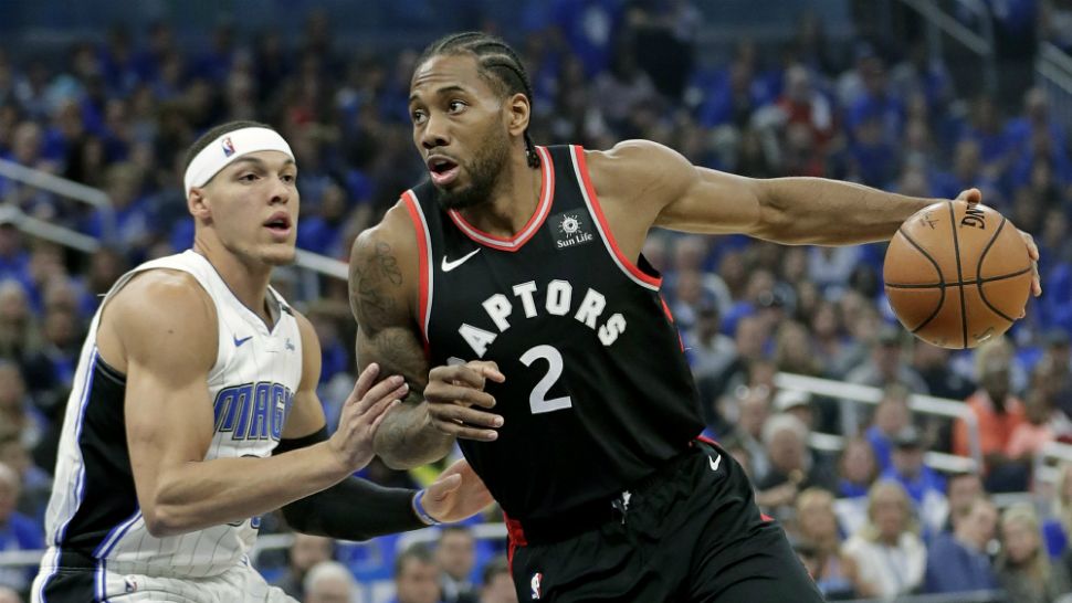 The Toronto Raptors' Kawhi Leonard (center) drives to the basket against the Orlando Magic's Aaron Gordon in the 1st half of Game 4 of their Eastern Conference playoff in Orlando. (John Raoux/AP)