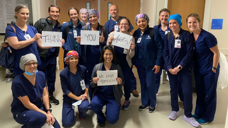 Health care workers hold up signs that read "Thank you Austin. We love Homeslice" (Courtesy: Frontline Foods))