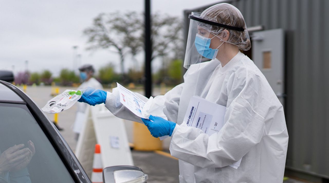 A person in protective gear administers a a drive-thru COVID-19 test in a Walmart parking lot (Courtesy: Walmart)