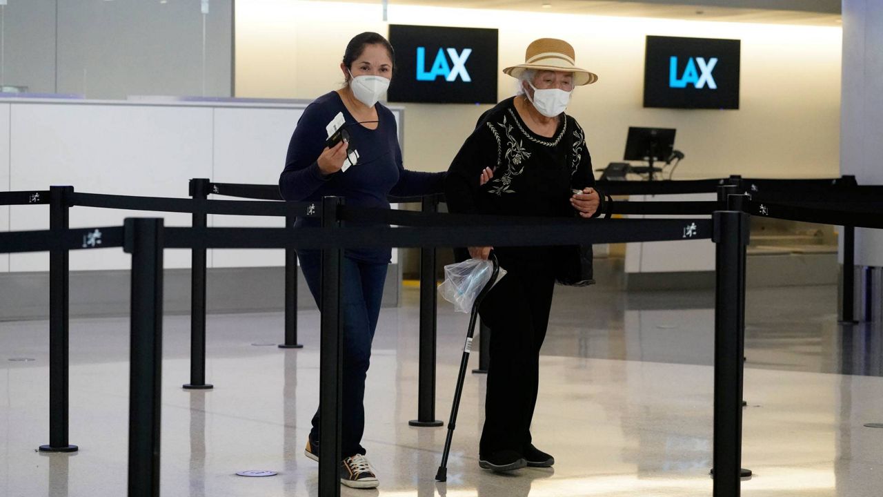 Travelers wear masks at a ticket counter at Los Angeles International Airport, April 25, 2022. (AP Photo/Marcio Jose Sanchez)