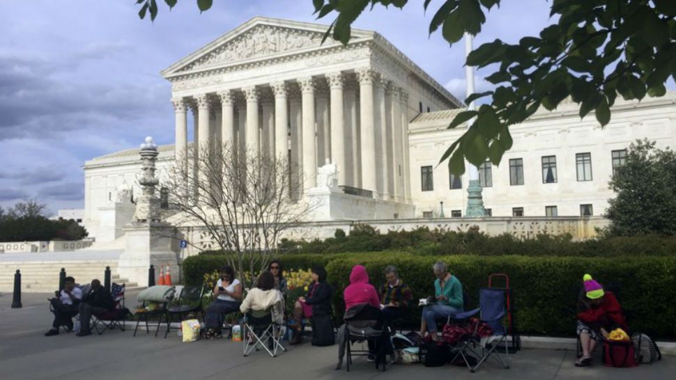 In this April 23, 2018, photo, people wait in line outside the Supreme Court in Washington, to be in the gallery when the court hears arguments in on April 25, over President Donald Trump’s ban on travelers from several mostly Muslim countries. (AP Photo/Jessica Gresko)