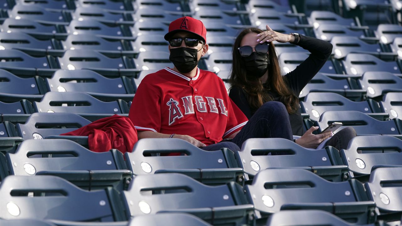 Fans wear masks as they watch batting practice before a baseball game between the Los Angeles Angels and the Houston Astros Monday, April 5, 2021, in Anaheim, Calif. (AP Photo/Marcio Jose Sanchez)
