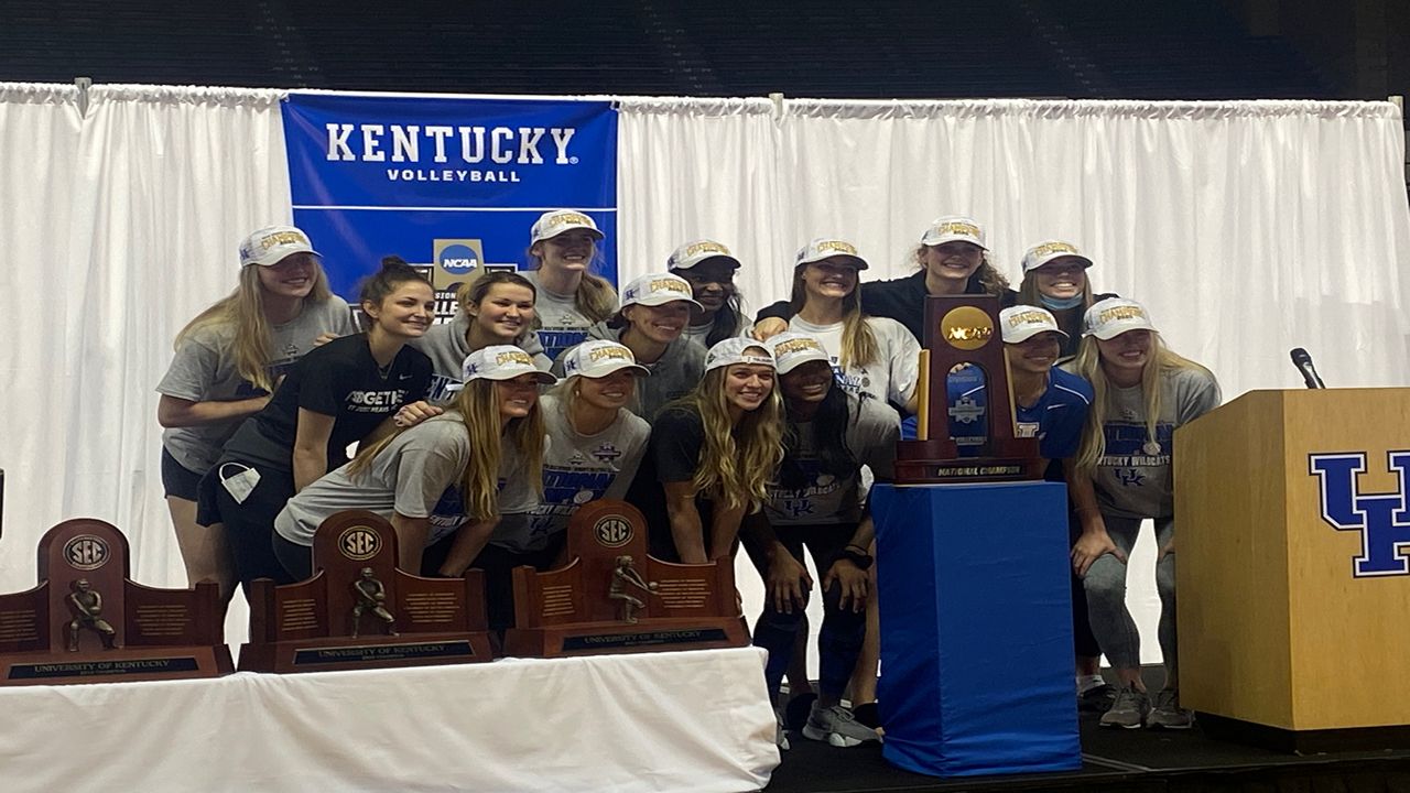 The UK volleyball team gather around their newly earned trophy for a picture.