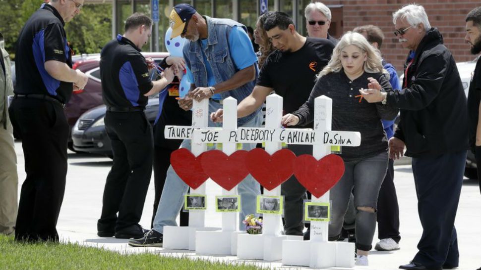 Family members of people killed at a Waffle House restaurant write messages on wooden crosses set up as a memorial Wednesday, April 25, 2018, in Nashville, Tenn. Four people were killed when a gunman opened fire at the restaurant Sunday. Members of the Waffle House management and staff joined the family members as the restaurant re-opened Wednesday. (AP Photo/Mark Humphrey)