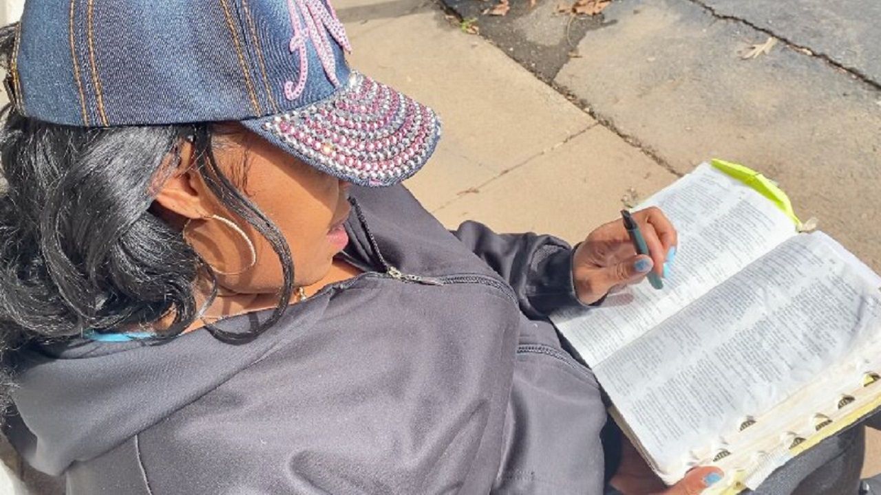 Woman experiencing homelessness sits outside Greensboro hotel
