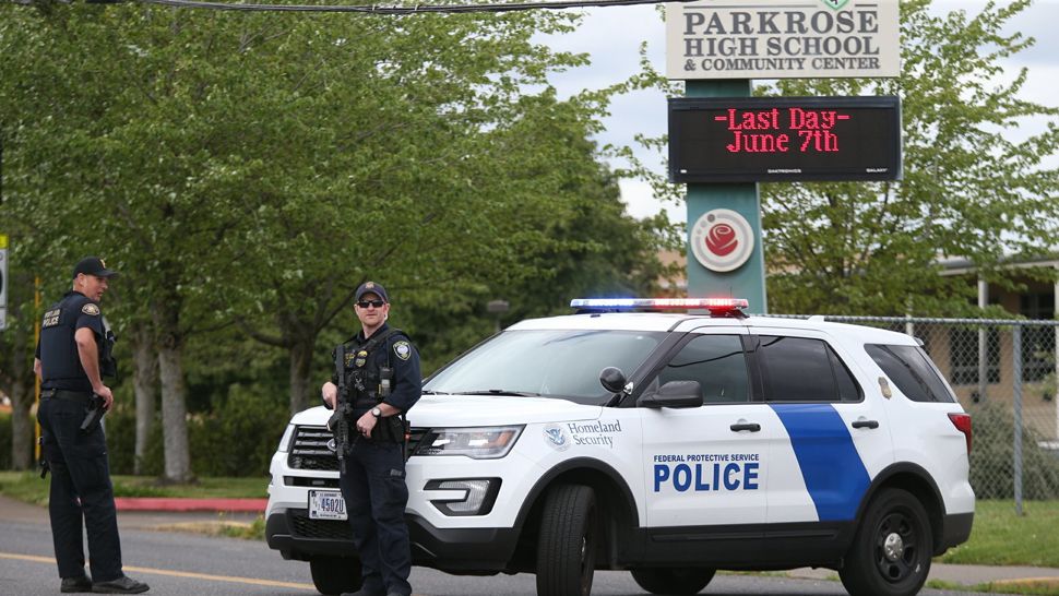 Police are positioned outside Parkrose High School Parkrose High School during a lockdown after a man armed with a gun was wrestled to the ground by a staff member, Friday, May 17, 2019 in Portland, Ore. The Portland Police Bureau said in a statement Friday that no shots were fired at Parkrose High School, no one was injured and the man is in custody. Police say there are no other suspects. (Dave Killen/The Oregonian via AP)