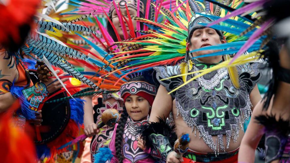 FILE - In this Monday, May 1, 2017, file photo, members of Ce Atl, an Aztec-inspired spiritual and cultural preservation group, dance near the front of a march for worker and immigrant rights at a May Day event in Seattle. The Donald Trump era has been everything that immigrant rights’ groups feared, but while they are taking to the streets again for May Day rallies in solidarity with those around the world, their focus this year is less on a huge turnout on a Tuesday in May than the first Tuesday in November. (AP Photo/Elaine Thompson, File)