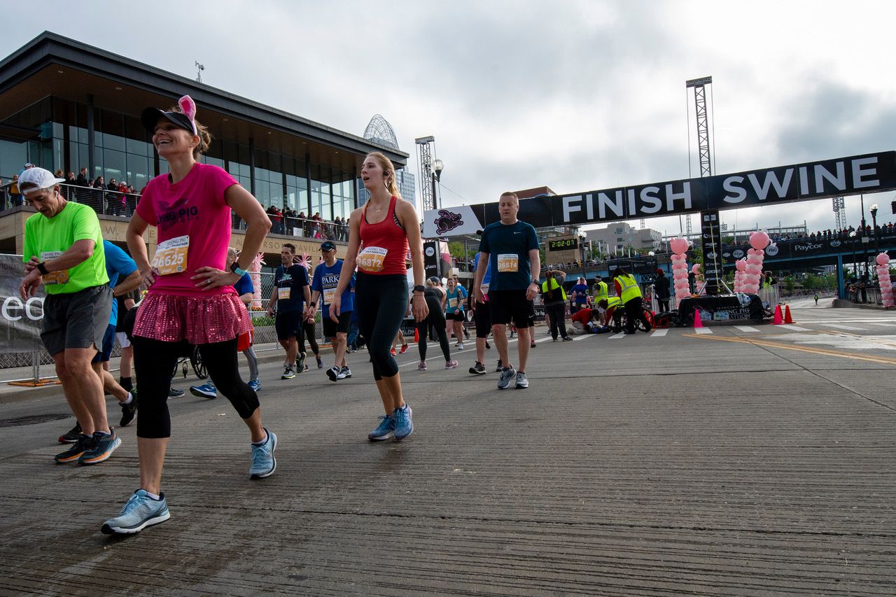 Racers, including a woman in a pig suit, smile after finishing a race during Flying Pig Marathon weekend. (Shae Combs/Game Day)