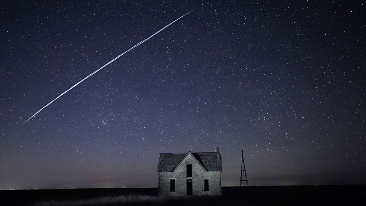 A long-exposure photo taken in May 2021 shows a string of Starlink satellites in orbit passing over a stone house in Kansas. (AP Photo/Reed Hoffmann)