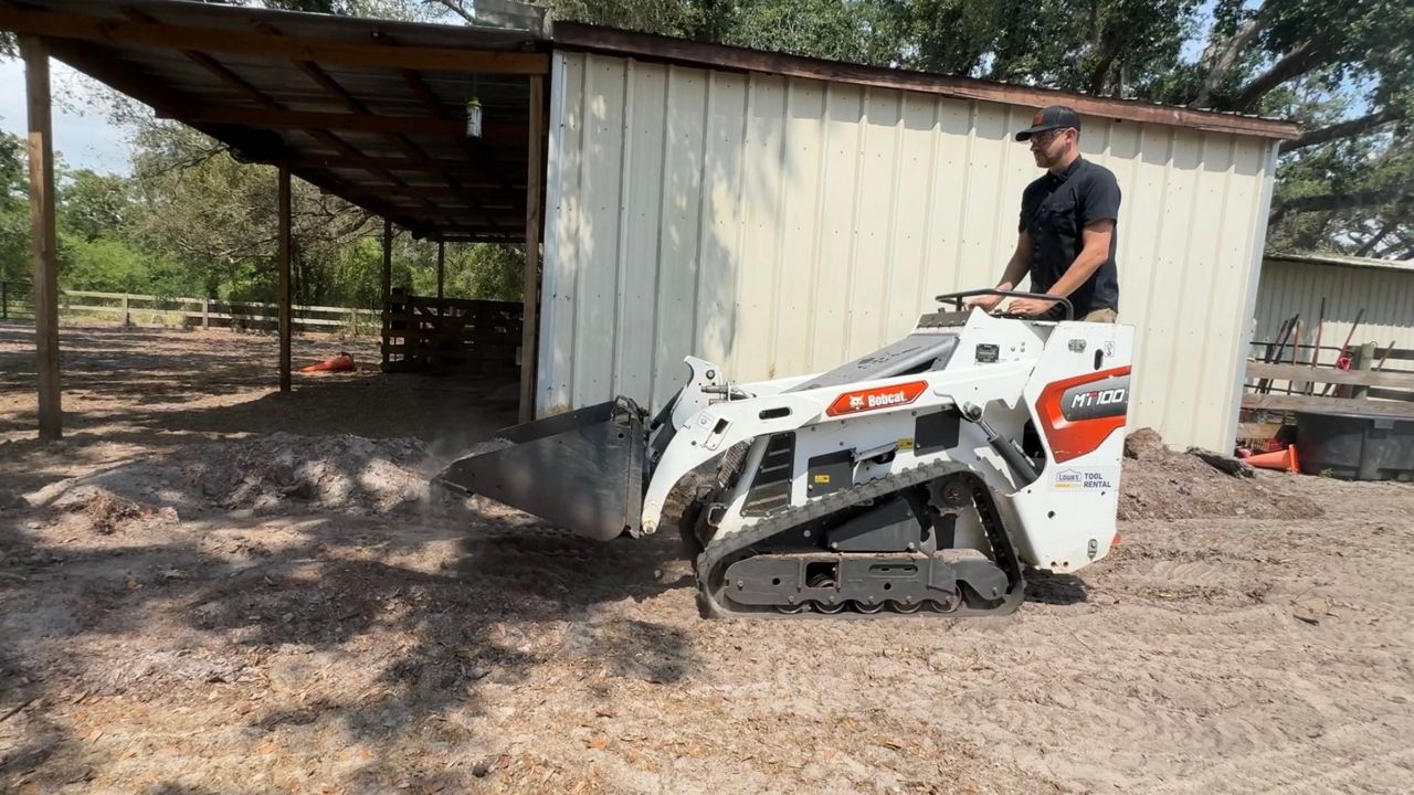 Bradley Anderson moves dirt to create a water drainage path on his Parrish property. (Spectrum Bay News 9/Julia Hazel)