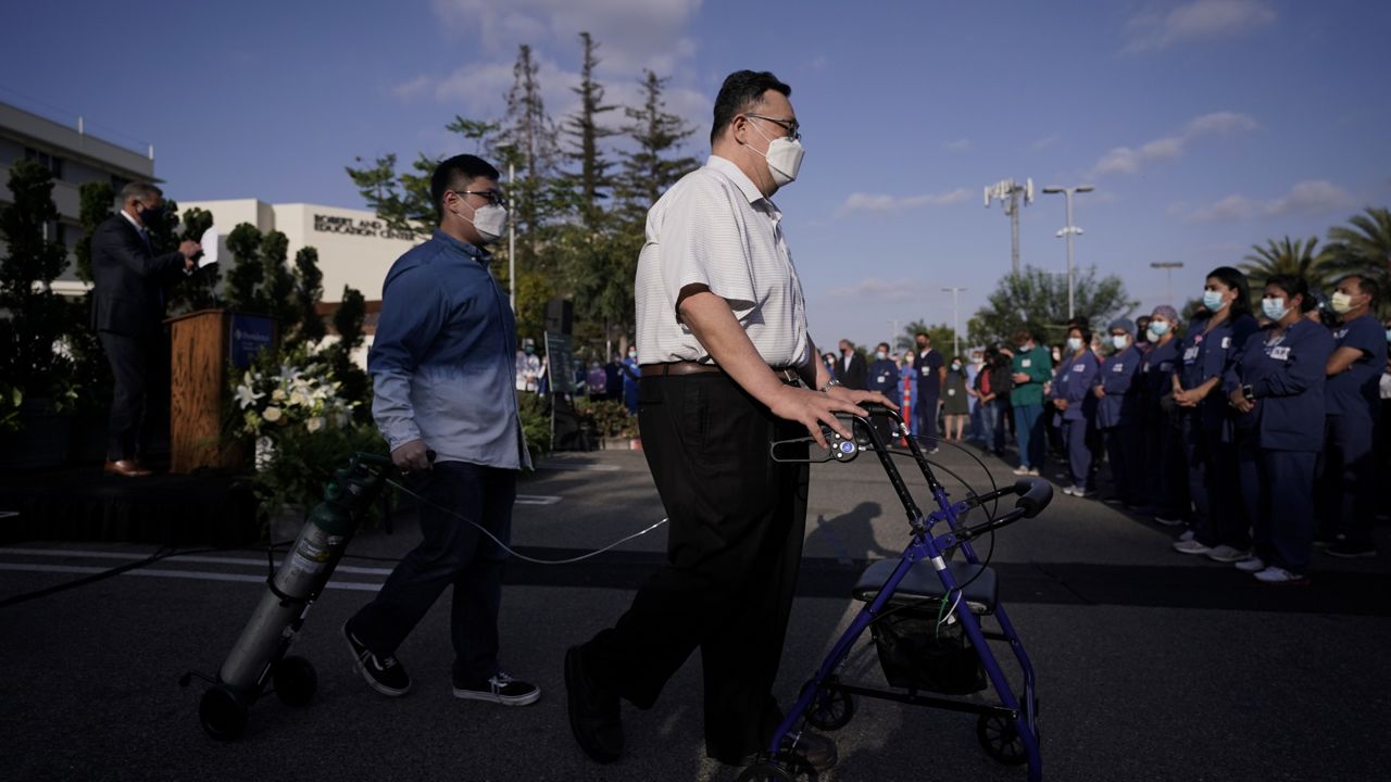 Daniel Kim, center, and his son Evan, carrying an oxygen tank, walk to join hospital staff members after delivering a speech at Providence St. Jude Medical Center in Fullerton, Calif., Monday, May 10, 2021. (AP Photo/Jae C. Hong)