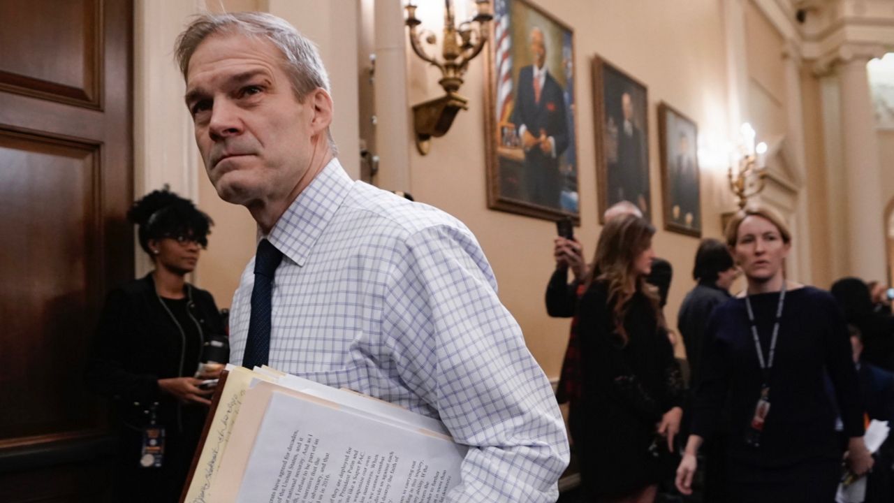 Rep. Jim Jordan holding a stack of files in Capitol hallway
