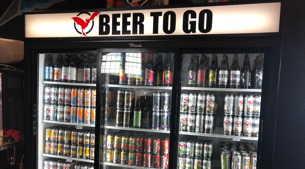 A refrigerator filled with beer with an illuminated sign that says "Beer To Go" (Spectrum News)