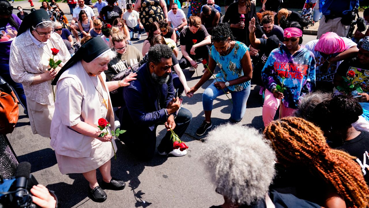 People pray outside the scene of a shooting at a supermarket in Buffalo, N.Y., Sunday, May 15, 2022. (AP Photo/Matt Rourke)