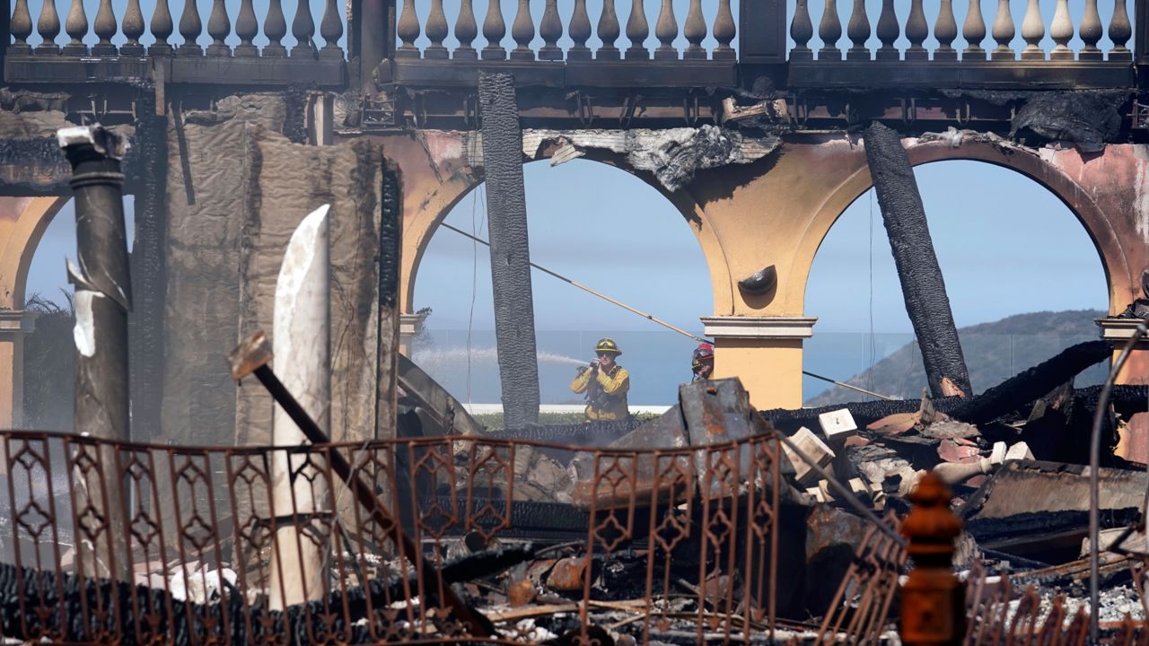 A firefighter hoses down hot spots from a home in the aftermath of the Coastal Fire Thursday, May 12, 2022, in Laguna Niguel, Calif. (AP Photo/Marcio Jose Sanchez)