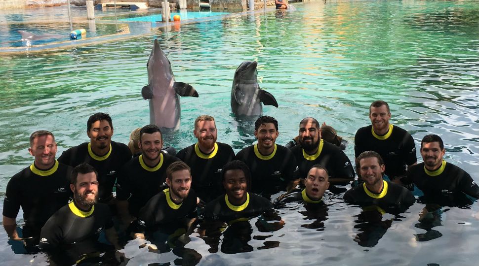 San Antonio Missions baseball team pose for a photo with the dolphins at SeaWorld May 15, 2019 (Spectrum News)