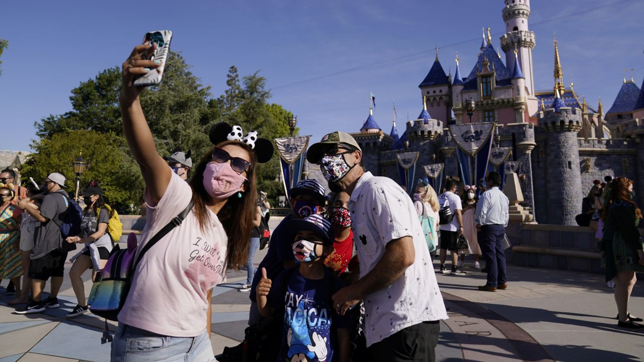 A family takes a photo in front of Sleeping Beauty's Castle at Disneyland in Anaheim, Calif. on April 30, 2021. (AP Photo/Jae Hong)