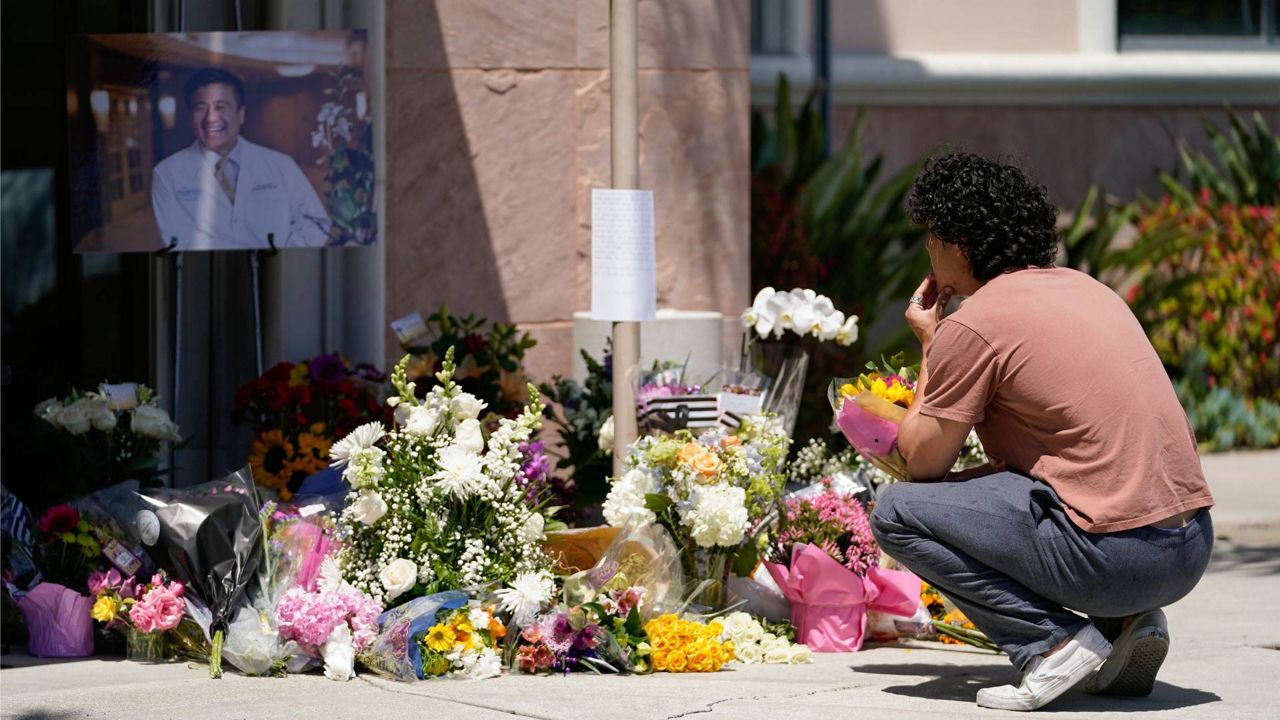 Gabe Kipers, a neighbor of Dr. John Cheng, kneels at a memorial for him outside his office building on May 17 in Aliso Viejo, Calif. Cheng, 52, was killed in a shooting at Geneva Presbyterian Church in Laguna Woods, Calif.. (AP Photo/Ashley Landis)