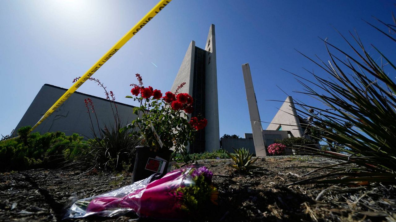 Flowers sit outside crime scene tape at Geneva Presbyterian Church Tuesday in Laguna Woods, Calif. In the wake of the recent shootings across the U.S., Los Angeles County’s top prosecutor has called for implementation of “reasonable gun control.” (AP Photo/Ashley Landis)