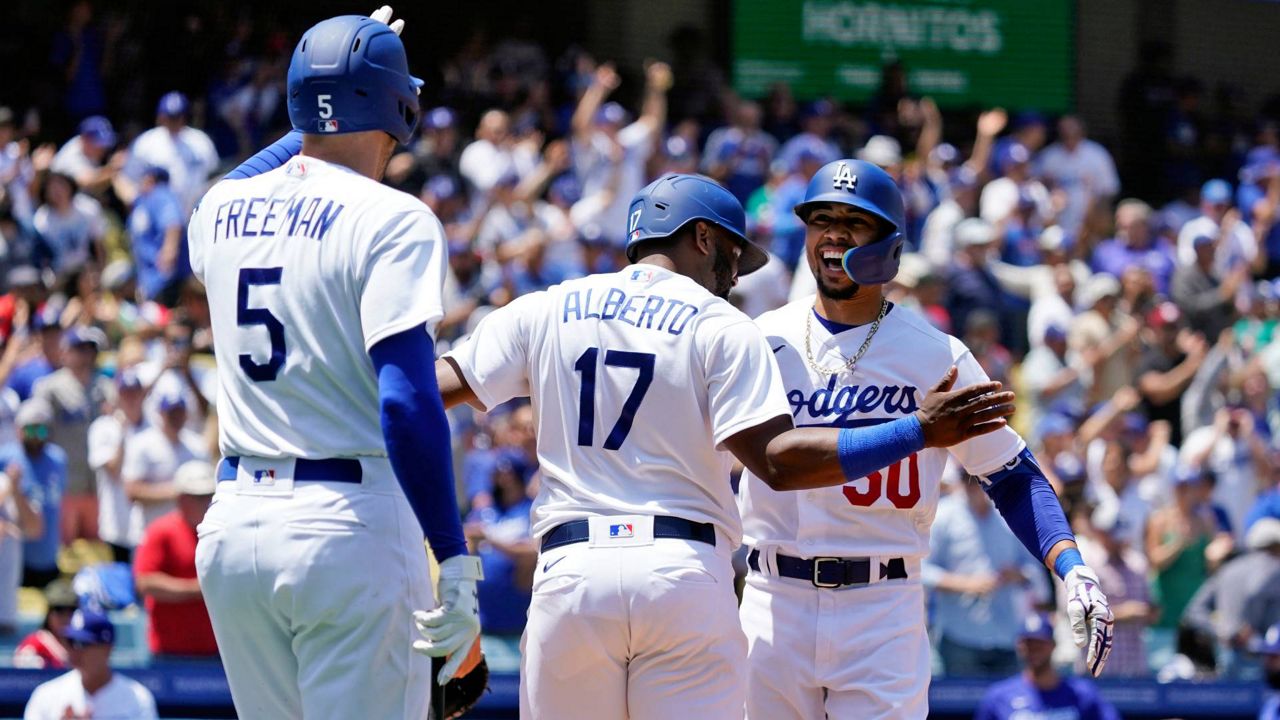 Los Angeles Dodgers' Mookie Betts, right, celebrates his two-run home run with Hanser Alberto (17) and Freddie Freeman (5) during the sixth inning of the first game of a baseball double-header against the Arizona Diamondbacks Tuesday in LA. (AP Photo/Marcio Jose Sanchez)