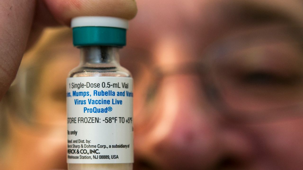 In this Thursday, Jan. 29, 2015 photo, pediatrician Charles Goodman holds a dose of the measles-mumps-rubella, or MMR, vaccine at his practice in Northridge, Calif. The vaccine is 99 percent effective at preventing measles, which spreads easily through the air and in enclosed spaces. Symptoms include fever, runny nose, cough and a rash all over the body. (AP Photo/Damian Dovarganes)