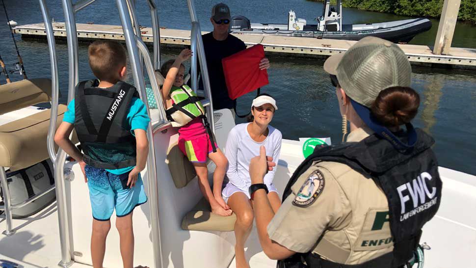 FWC Officer Ashley Tyer speaks to boaters while checking to confirm they were carrying proper safety equipment. (Trevor Pettiford/Spectrum Bay News 9)