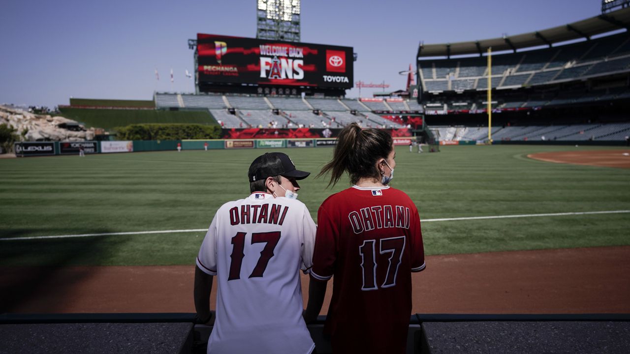Two fans of Los Angeles Angels' Shohei Ohtani, of Japan, look onto the field before the team's baseball game against the Cleveland Indians, Wednesday, May 19, 2021, in Anaheim, Calif. (AP Photo/Jae C. Hong)