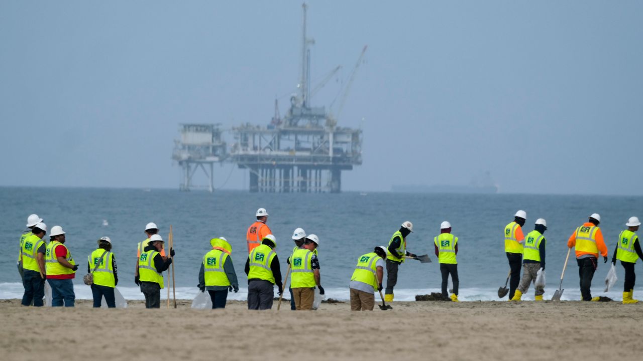 Workers in protective suits continue to clean the contaminated beach with a platform in the background in Huntington Beach, Calif., on Oct. 11, 2021. (AP Photo/Ringo H.W. Chiu, File)