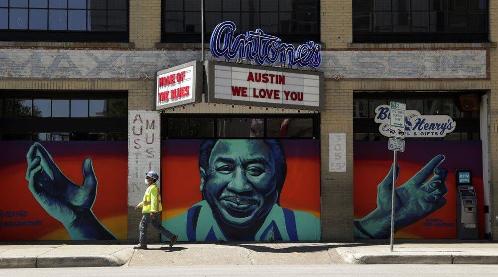 A worker passes a nightclub that remains boarded and closed in Austin, Texas, Monday, May 18, 2020. (AP Photo/Eric Gay)