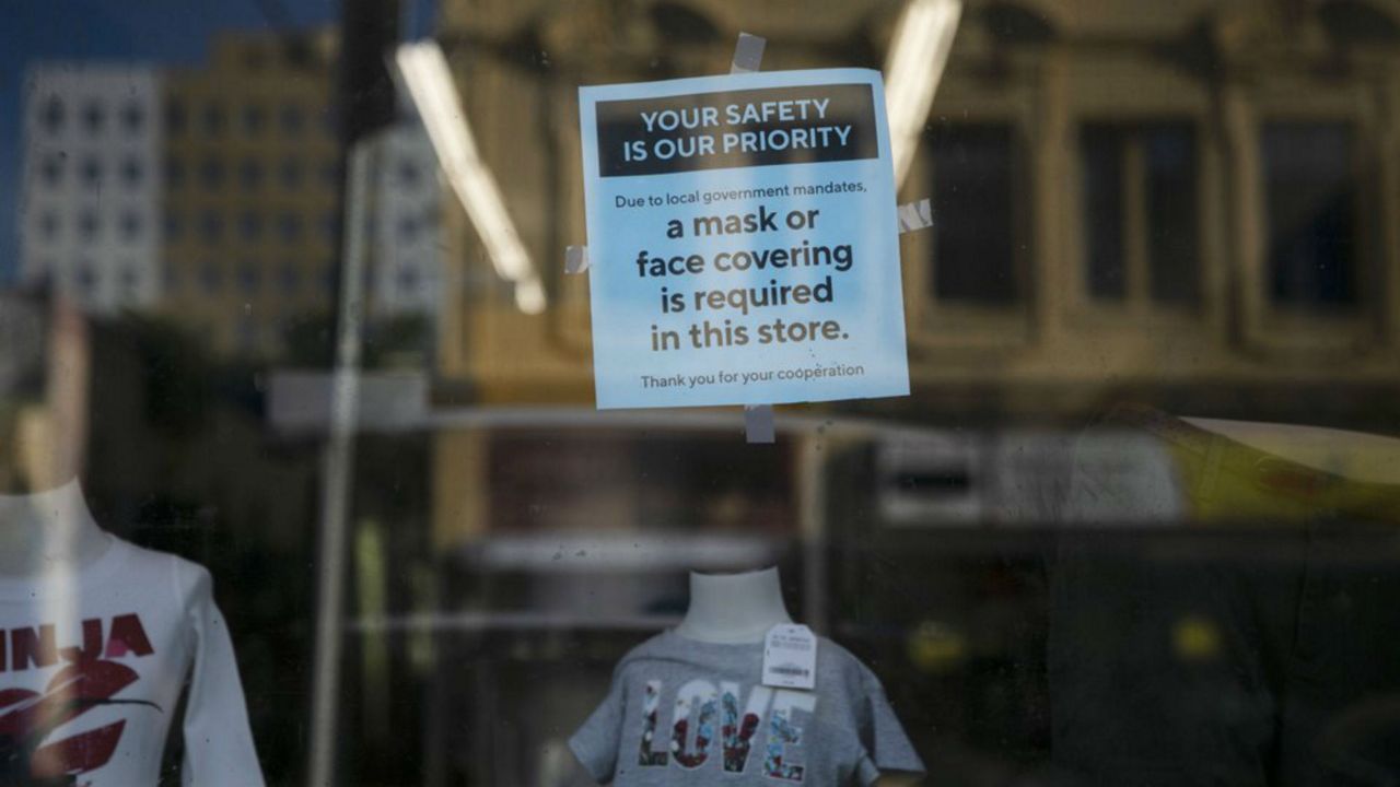 A sign requiring face masks is posted on the window of a clothing store during the coronavirus pandemic in the Westlake neighborhood of Los Angeles, Thursday, May 21, 2020. While most of California took another step forward to partly reopen in time for Memorial Day weekend, Los Angeles County didn't join the party because the number of coronavirus cases has grown at a pace that leaves it unable to meet even the new, relaxed state standards for allowing additional businesses and recreational activities. (AP Photo/Jae C. Hong)