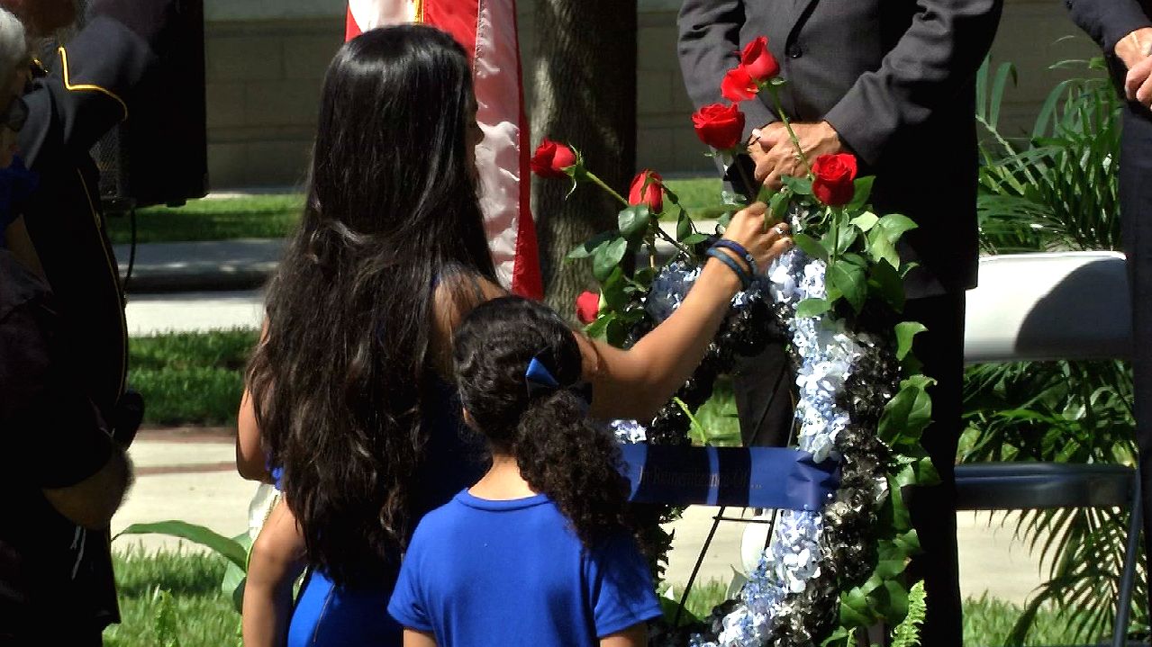 Woman placing rose on wreath honoring Kissimmee's fallen law enforcement officers.