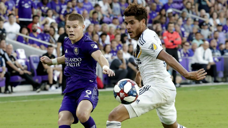 Orlando City's Chris Mueller (9) takes a shot past LA Galaxy's Jonathan dos Santos during the first half of an MLS soccer match Friday, May 24, 2019, in Orlando, Fla. (AP Photo/John Raoux)