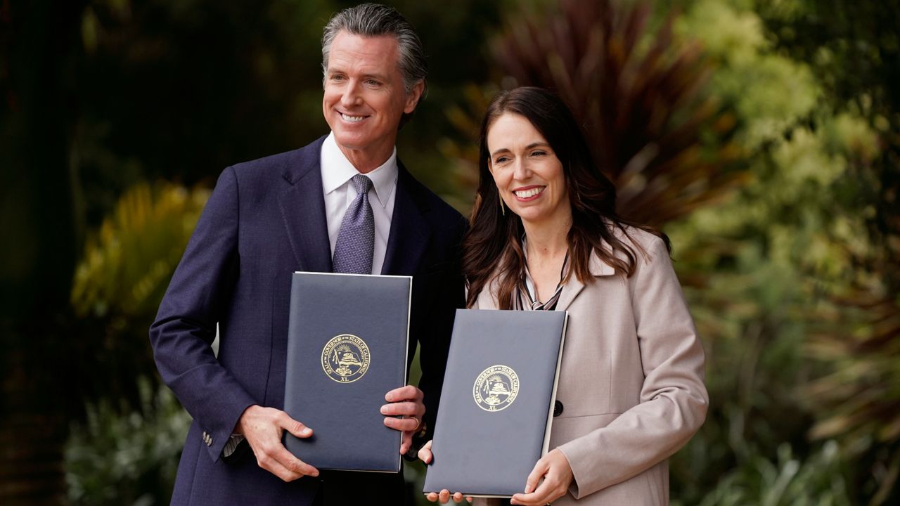 California Gov. Gavin Newsom and New Zealand Prime Minister Jacinda Ardern pose with agreements they signed at the San Francisco Botanical Garden in San Francisco, Friday, May 27, 2022. (AP Photo/Eric Risberg)