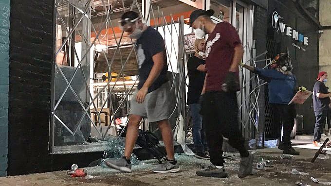 People walk by a business with busted windows on 6th Street in Austin, Texas (Matt Mershon/Spectrum News)