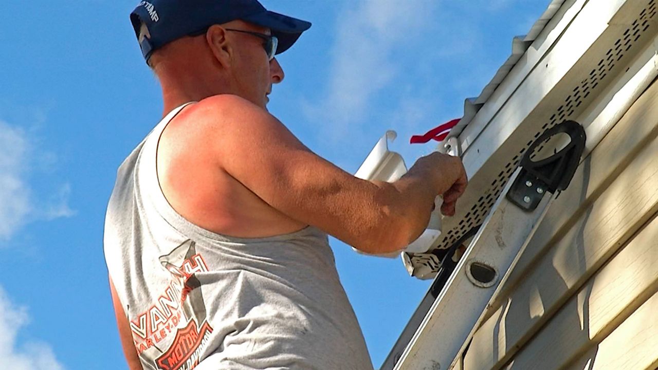 Before any possible storm hits, they are emphasizing having an evacuation route, trimming trees and brushes, creating a disaster preparedness kit that includes a flashlight, three days' worth of food and water, and a first aid kit.  (File photo of a man preparing his roof before a storm)