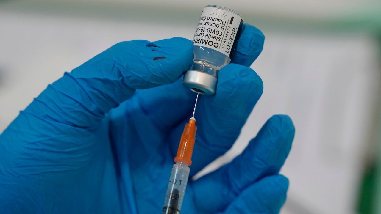Someone draws a COVID-19 vaccine into a syringe. (Associated Press)
