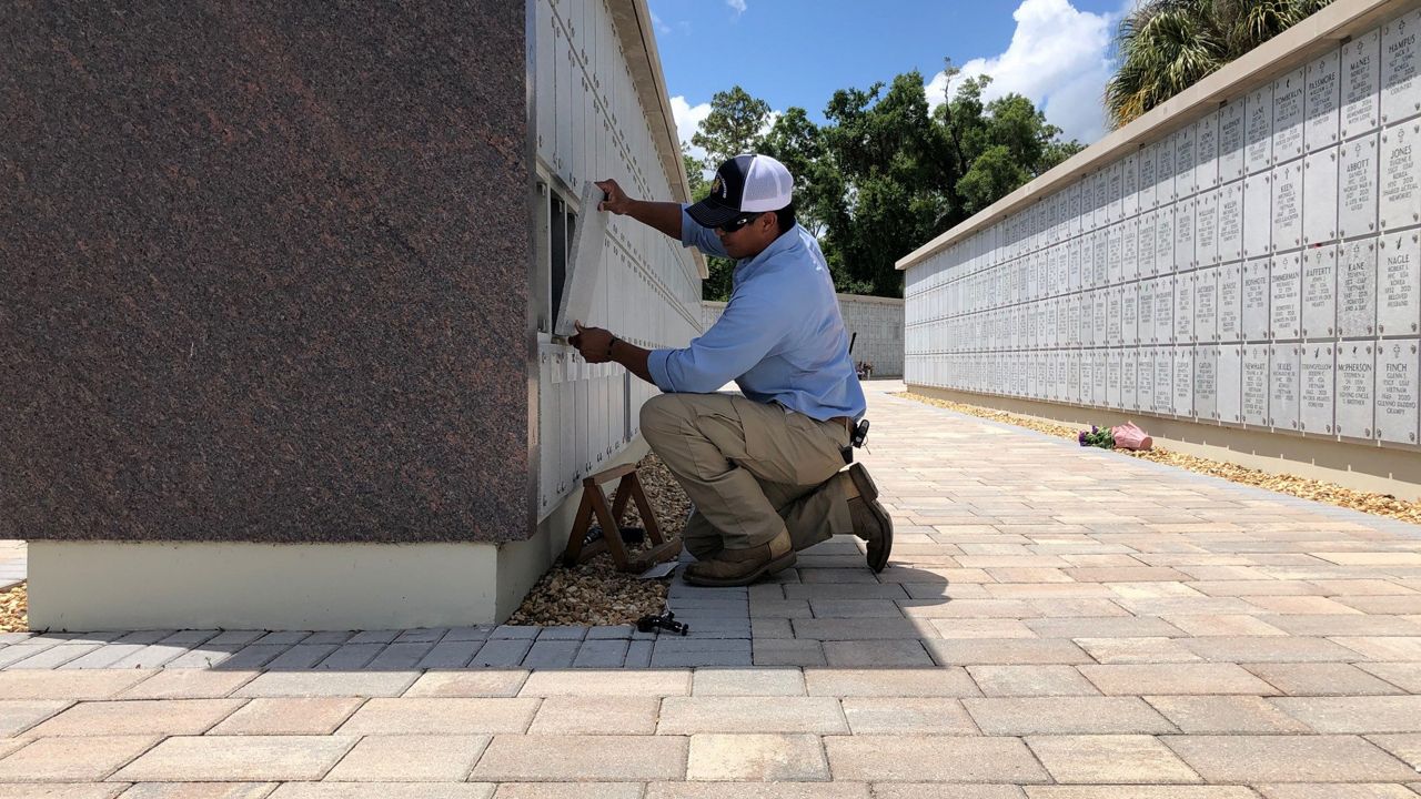 Arcel Sabilona seals remains into one of the columbariums at Florida National Cemetery in Bushnell. (Spectrum News/Erin Murray)