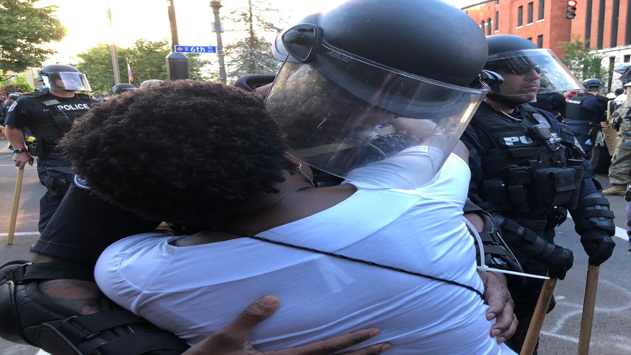 An officer and a woman hug during protest