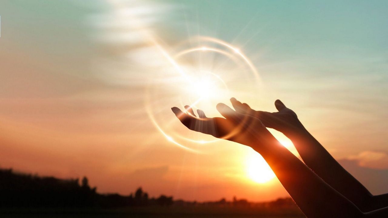 Praying hands with light rays