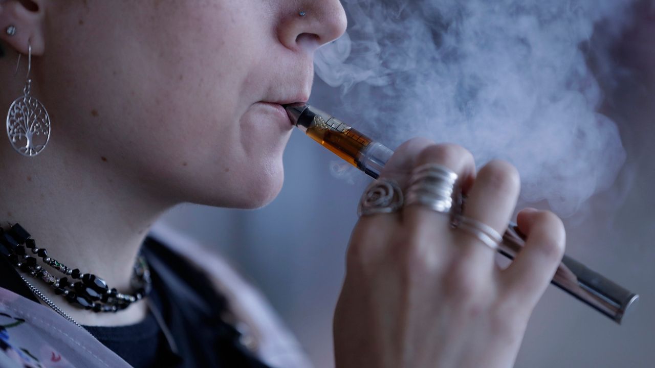 In this Friday, Oct. 4, 2019 photo, a woman using an electronic cigarette exhales in Mayfield Heights, Ohio. (AP Photo/Tony Dejak)